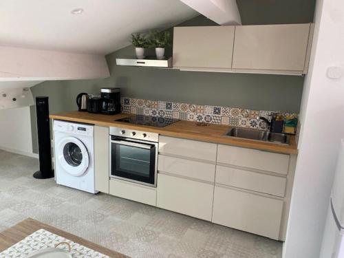 a kitchen with a washing machine and a washer at Cozy studio with terrace and view Collobrières in Collobrières