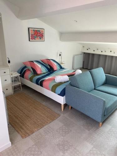 a bedroom with a bed and a blue couch at Cozy studio with terrace and view Collobrières in Collobrières