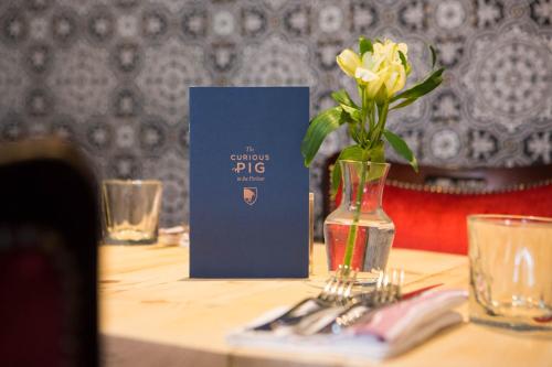 a table with a vase with a flower in it at The Curious Pig in the Parlour in Burstow