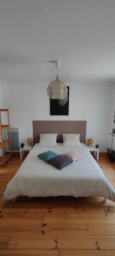 - une chambre avec un grand lit et un mur blanc dans l'établissement les Lys Jolie suite parentale privative deux adultes avec sdd, à Pertheville-Ners