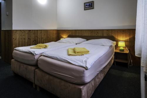a bedroom with a bed with two yellow towels on it at Hotel Bellevue in Jetřichovice