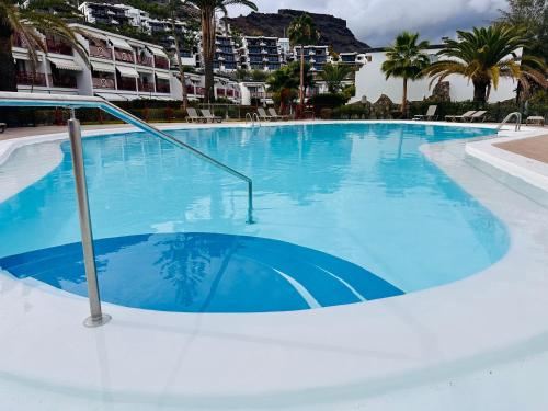 a large blue swimming pool with palm trees and buildings at PLAYA DEL CURA - Spacious Beachside Apartment in Playa del Cura