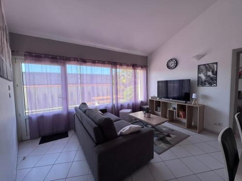 a living room with a couch and a tv at Dunes Apart-Hotel - Kiwi Residence in Aytré