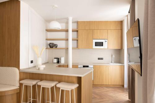 une cuisine avec des armoires en bois et un comptoir avec des tabourets dans l'établissement Exclusive apt with AC - 2BD-6P - Quartier Latin, à Paris