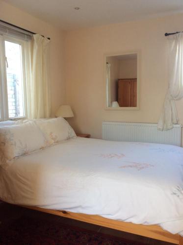 a bedroom with a white bed with a window at The White Barn near Cambridge in Huntingdon