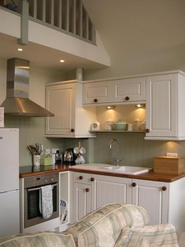 a kitchen with white cabinets and a sink at The White Barn near Cambridge in Huntingdon