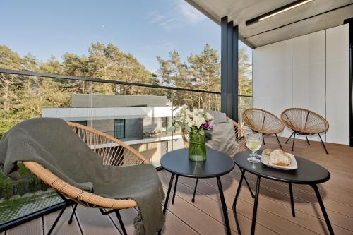 a patio with chairs and tables on a balcony at Apartamenty Wydma & Las BlueApart in Jastarnia