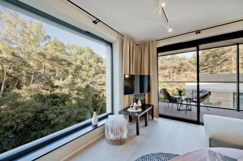 a living room with a large window and a dining room at Apartamenty Wydma & Las BlueApart in Jastarnia