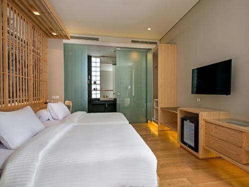 a bedroom with a large bed and a flat screen tv at Tama Boutique Hotel in Bandung