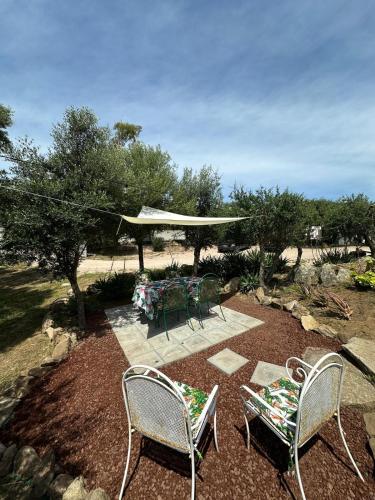 a patio with chairs and a table and umbrella at Casa Mariposa Porto Rotondo in Rudalza