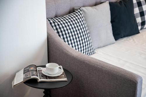 a coffee cup and a newspaper on a table next to a couch at Resort Suites at Pyramid Tower by GL Staycation in Petaling Jaya