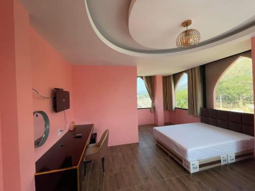 a bedroom with pink walls and a bed and a desk at The Morocco in Kaeng Krachan