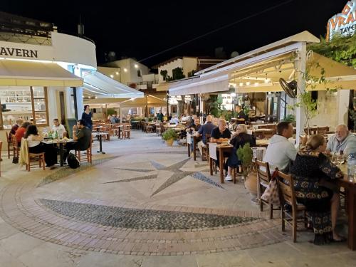 people sitting at tables at an outdoor restaurant at night at Rantzo Holiday Apartments in Pissouri