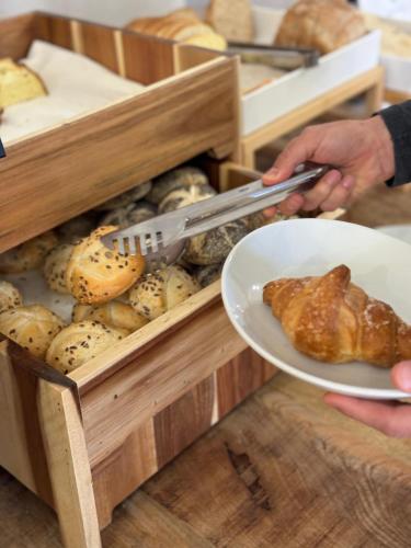een persoon met een bord brood en croissants bij 4 Mori Family Village - Villaggio per Famiglie in Muravera