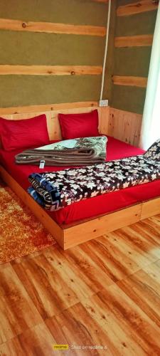a wooden bed in a room with red pillows at Mysterious Kutla Cottage,Kutla, Tosh in Chhorang
