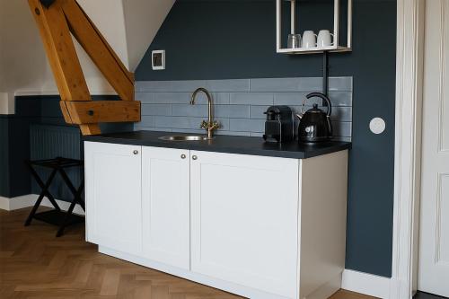 a kitchen with white cabinets and a sink at Boetiekhotel Ons Oude Raadhuis in Hooge Zwaluwe