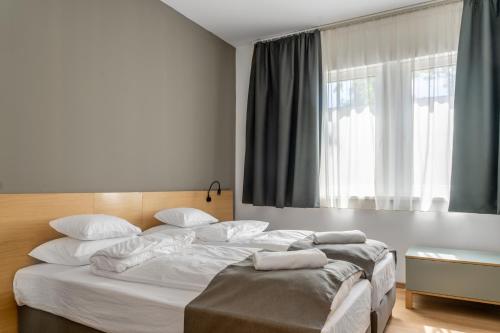 a bedroom with a large white bed with a window at Rákóczi Hotel, Tábor és Rendezvényközpont in Sátoraljaújhely