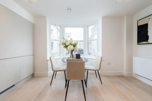 a dining room with a table with chairs and a vase of flowers at VESTO Stays Brighton in Brighton & Hove