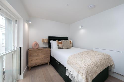 a white bedroom with a bed and a window at VESTO Stays Brighton in Brighton & Hove