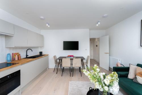 a kitchen and living room with a table and a green couch at VESTO Stays Brighton in Brighton & Hove
