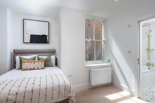 a white bedroom with a bed and a window at VESTO Stays Brighton in Brighton & Hove