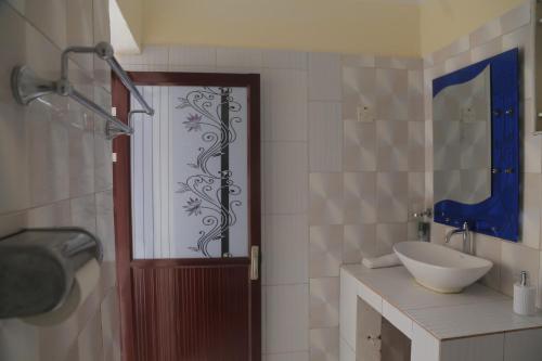 ein Bad mit Dusche und eine Tür mit Waschbecken in der Unterkunft Beautiful Spaces 3 bedroomed bungalow in Kira