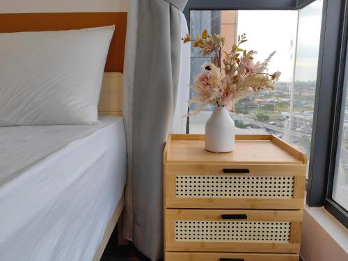 a bedroom with a bed and a vase with flowers on a table at K Avenue Modern Style Studio (5 Mins to Airport) in Kota Kinabalu