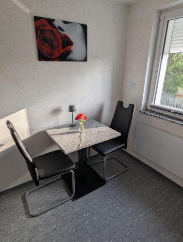 a table with two chairs and a vase with flowers on it at Apartment in Lehrte