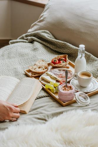 a breakfast tray with food and a book on a bed at Életem Vendégház in Esztergom