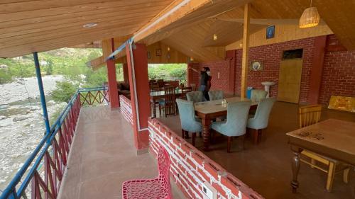 a restaurant with a table and chairs on a balcony at Usha River Side Resort in Gushaini