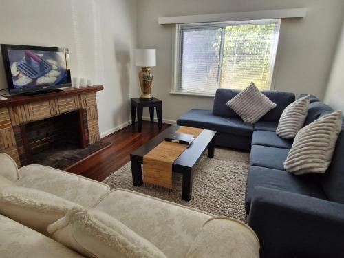 a living room with blue couches and a fireplace at Heart of Lathlain in Perth
