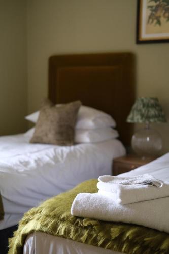 a room with two beds with white sheets and towels at The Peacock at Barlow in Chesterfield