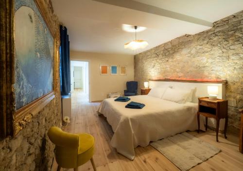 une chambre avec un grand lit et un mur en pierre dans l'établissement Charming House In The Heart Of Dordogne, à Monpazier