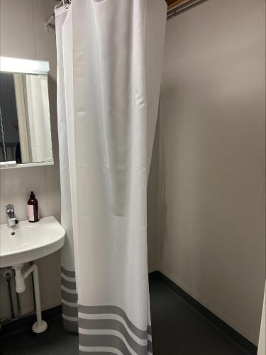 a bathroom with a white shower curtain next to a sink at Puomitie for 3 persons in Kajaani