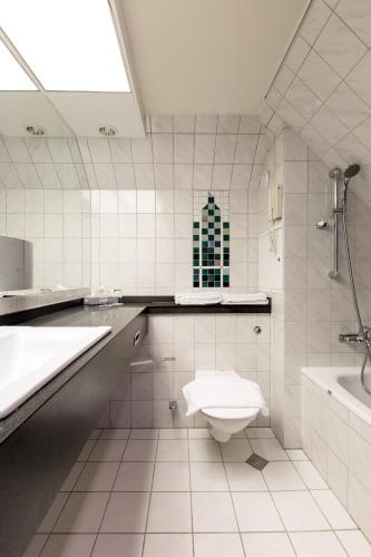 a bathroom with a toilet and a sink and a tub at Best Western Plus Hotel Plaza in Västerås