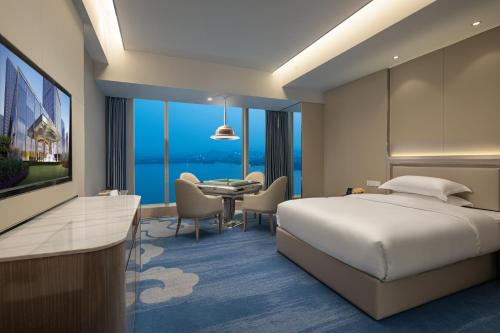 a hotel room with a bed and a dining room at Wyndham Shaoxing Keqiao in Shaoxing