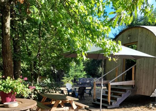 un patio con un tavolo e un ombrellone di " village tonneaux de tirpoil " a Montilliers
