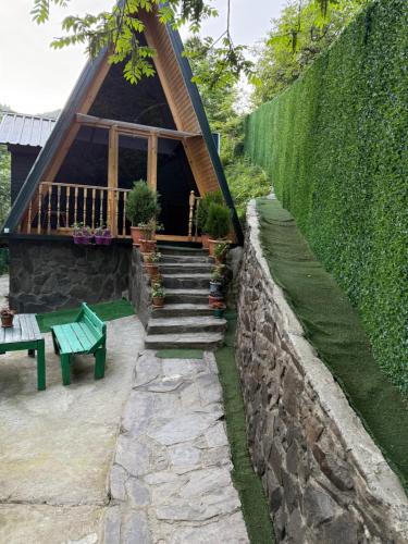 a house with a stone wall and a green bench at xedi in Itʼkhvisi