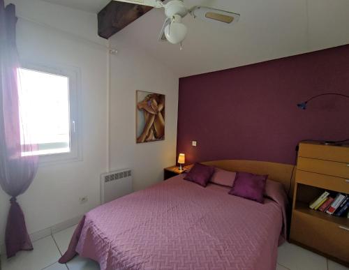 une chambre avec un lit violet et une fenêtre dans l'établissement Villa 17, Cap Sauvage au village naturiste, au Cap d'Agde