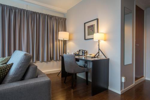a hotel room with a desk and a couch and a room at Best Western Plus Hotel Plaza in Västerås