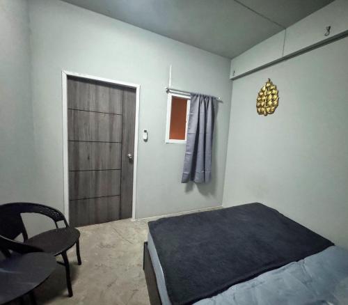 a bedroom with a bed and a chair and a door at Penny Hostel & Cafe in Thongsala