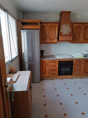 a kitchen with wooden cabinets and a stainless steel refrigerator at Casa Rural Chalet Venta del Aire Cortijo Terron in Lanjarón