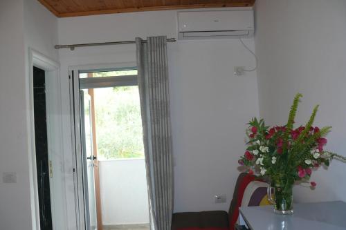 a room with a window with a vase of flowers on a table at Hotel Erviliano in Borsh