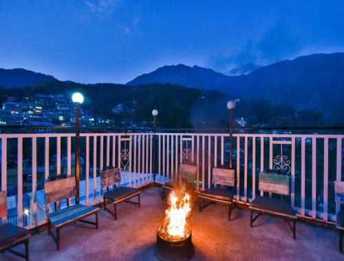 a fire pit on a balcony with a view of the mountains at LA Riqueza Koala Inn Mcleo Ganj # Close to Mall Road # Rooftop Restaurant with Mountain View # In-house Parking in McLeod Ganj