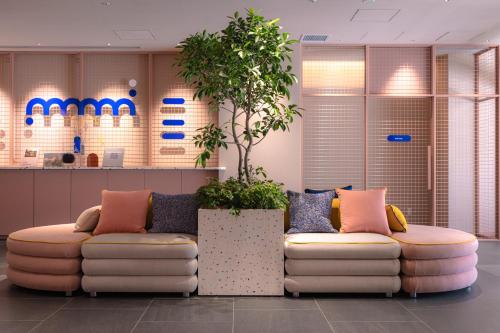 a lobby with two couches and a potted plant at THE BASEMENT HOTEL OsakaHonmachi in Osaka