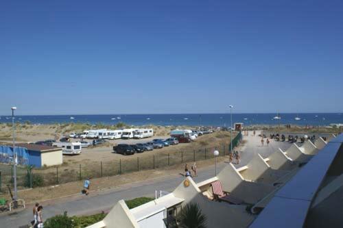 un parking avec un tas de tentes et l'océan dans l'établissement Studio 232, Héliopolis AB au village naturiste, au Cap d'Agde