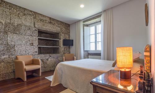 1 dormitorio con cama y pared de piedra en Pazo de Sedor, en Arzúa