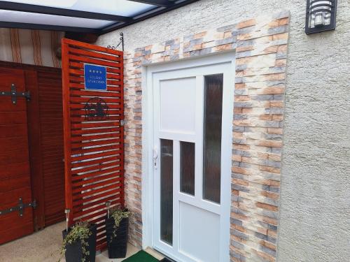 a white door on the side of a brick building at Studio Spa Sweet Nest jacuzzi-sauna-bazen in Otočac