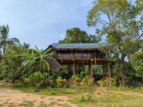 a tree house with a deck in a field at Sigiriya Rock View Tree house in Sigiriya