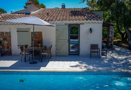 une maison avec une table et des chaises à côté d'une piscine dans l'établissement Villa des Chênes, à Roquebrune-sur Argens